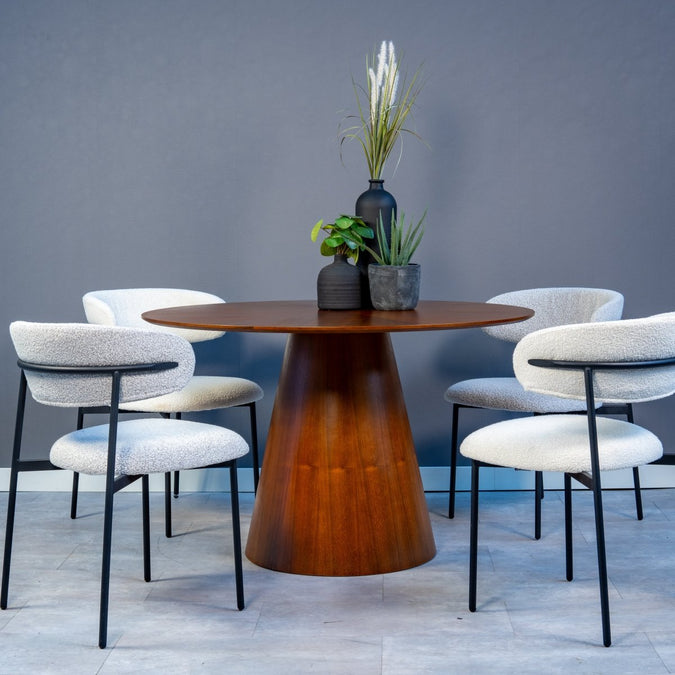 Runder dunkelbrauner Holztisch mit vier weißen Stühlen.