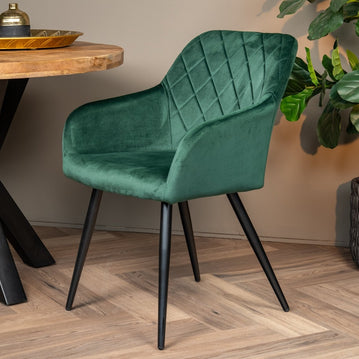 Dunkelgrüner Esszimmerstuhl mit schwarzen Beinen.