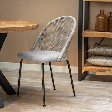 Grauer Esszimmerstuhl mit geflochtener Rückenlehne und schwarzen Beinen.