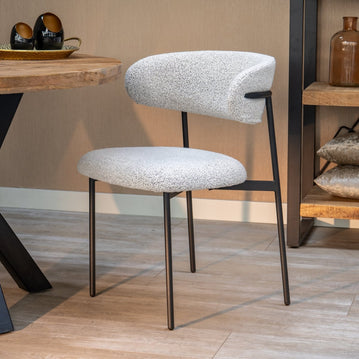 Weißer Stoff-Esszimmerstuhl mit schwarzen Beinen.