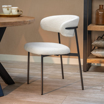 Weißer Esszimmerstuhl mit schwarzen Beinen.